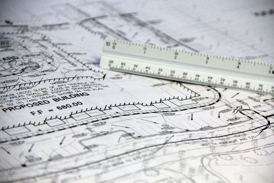 Architectural blueprints with a scale ruler, showing building plans and measurements