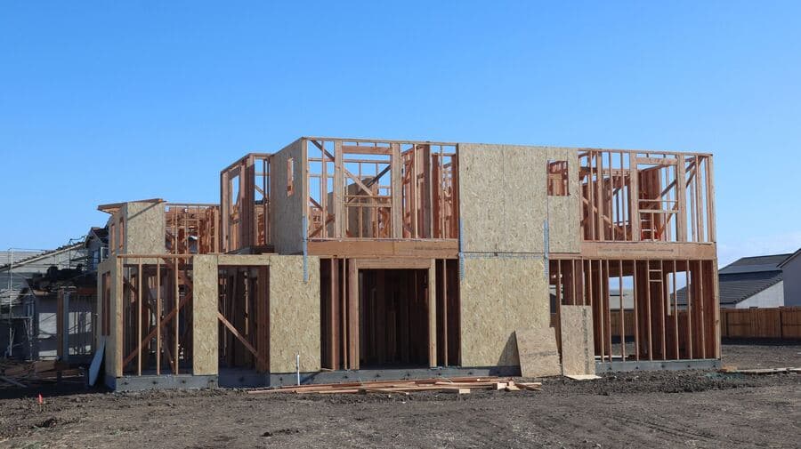 A wooden frame structure under construction for a new suburban house